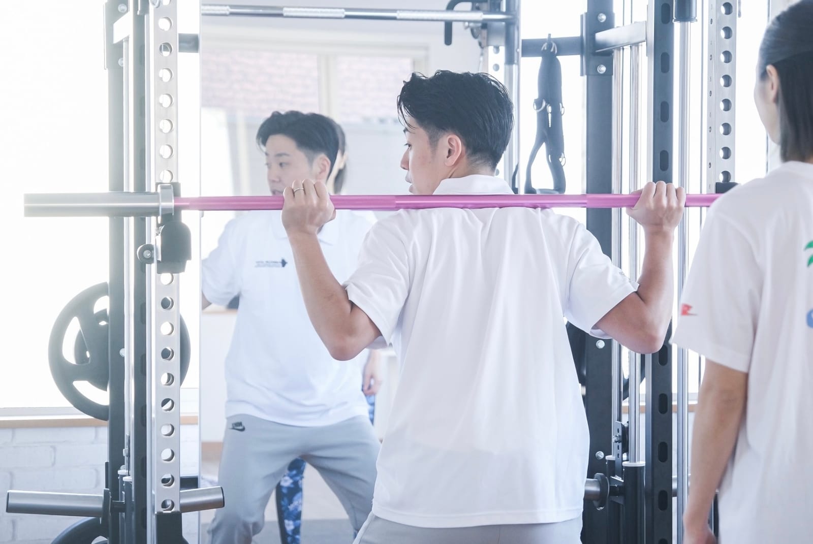 ANCHOR FITで、トレーナーがラックの横に立って利用者のフォームを1対1で見ている様子